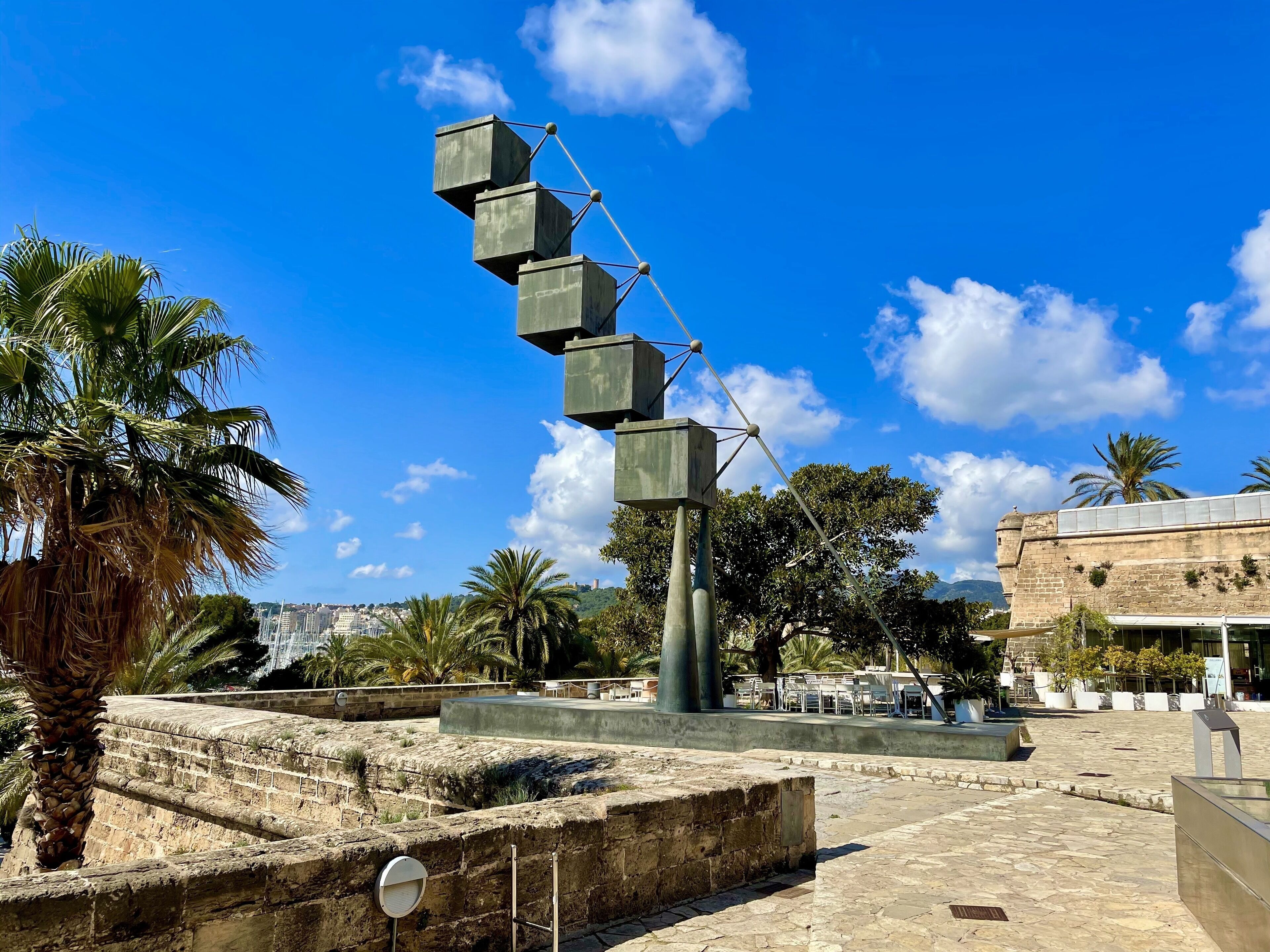 Un site historique composé d’une série de marches en pierre menant à une plateforme d’observation, entouré de palmiers et surplombant un ciel d’un bleu limpide.