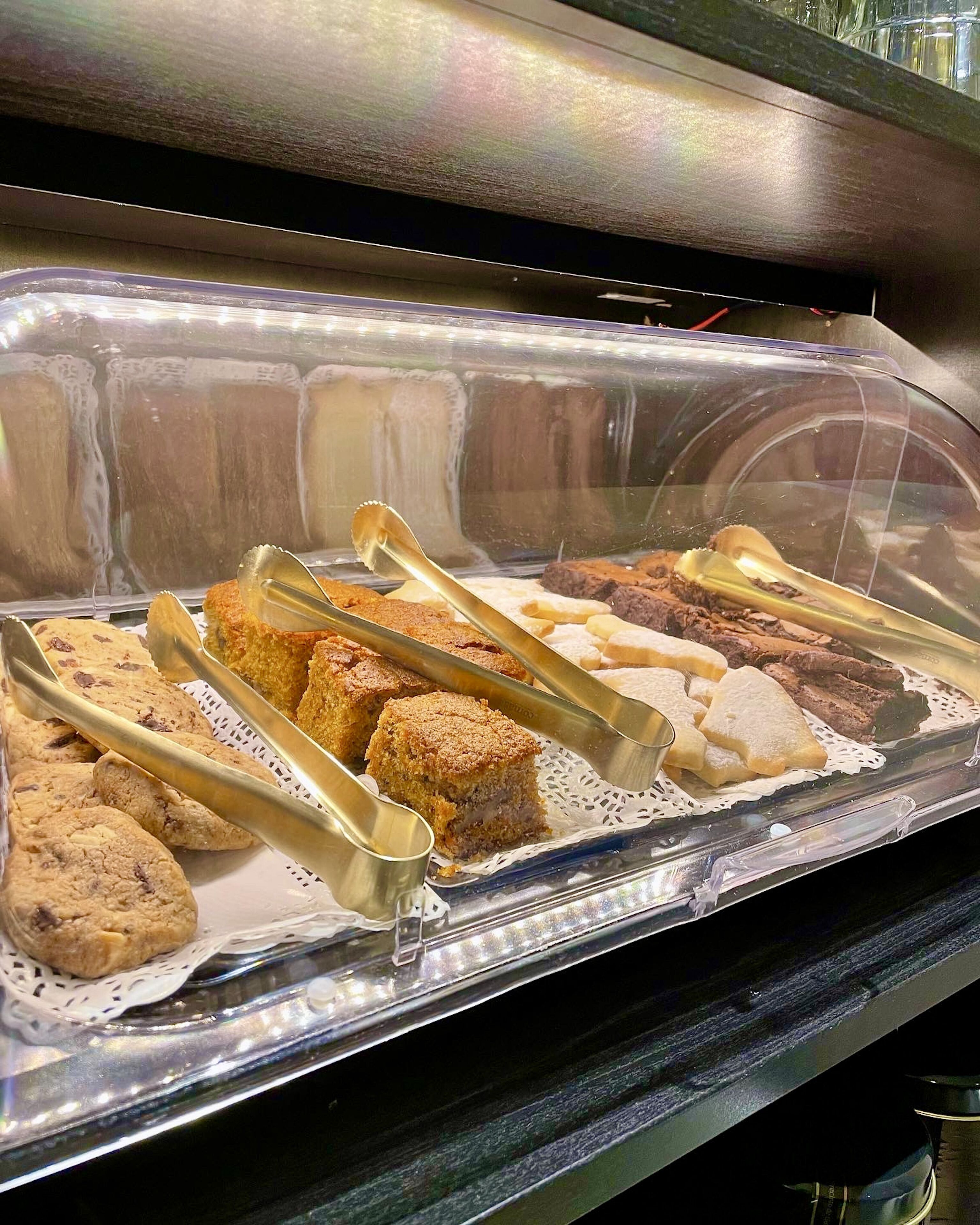 Buffet com diversos produtos de panificação, incluindo biscoitos, bolos e brownies.