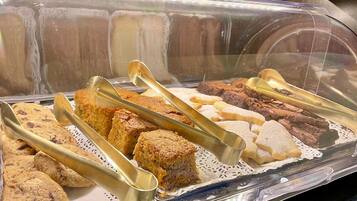 Buffet com diversos produtos de panificação, incluindo biscoitos, bolos e brownies.