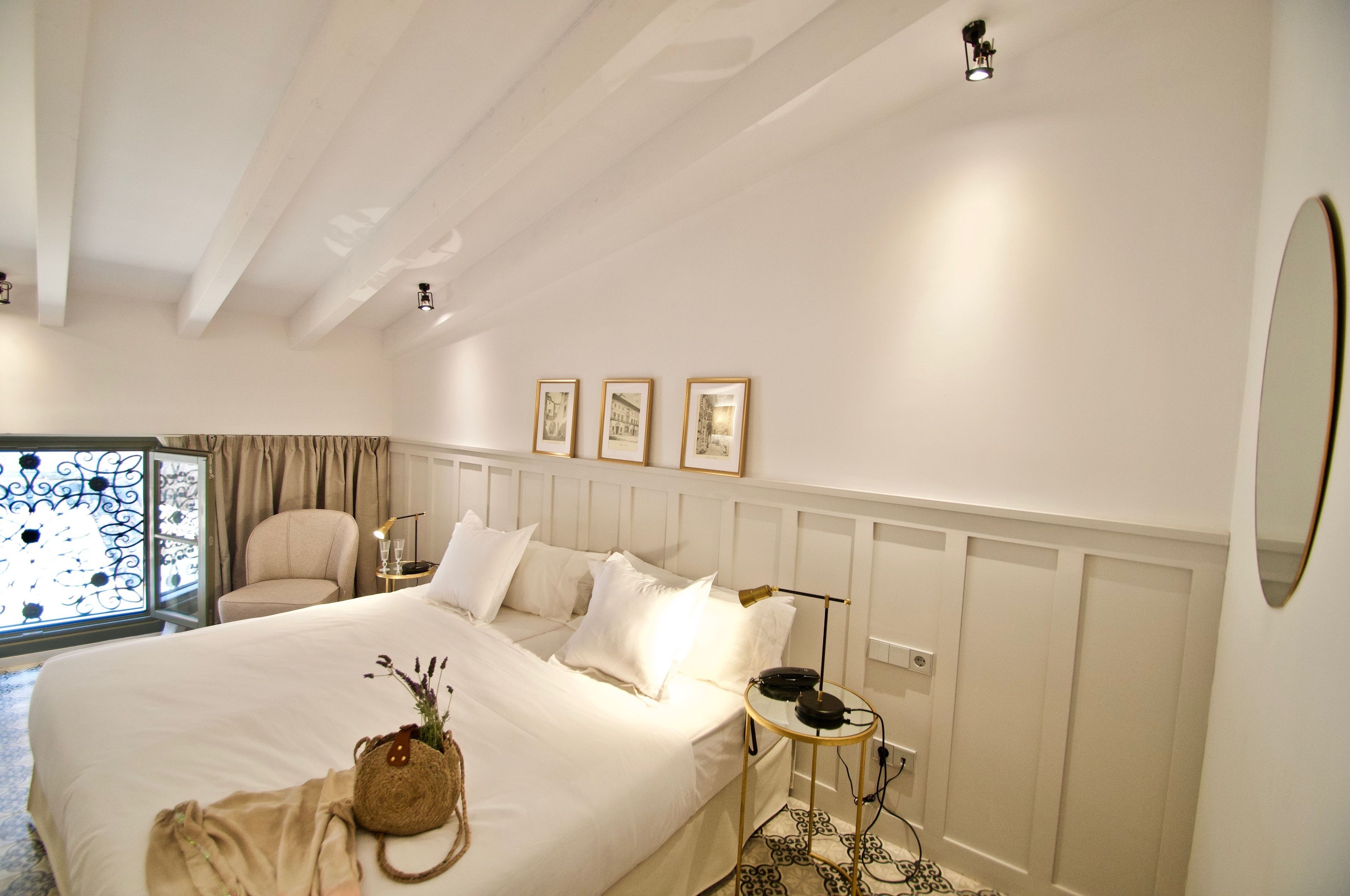 A hotel room with a large bed, a bedside table, a chair, and a window with curtains.