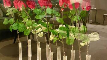 A series of rose plants in transparent vases on a reflective surface.