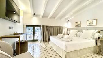 A hotel room with a bed, a desk, a chair, a TV, and a window with curtains.