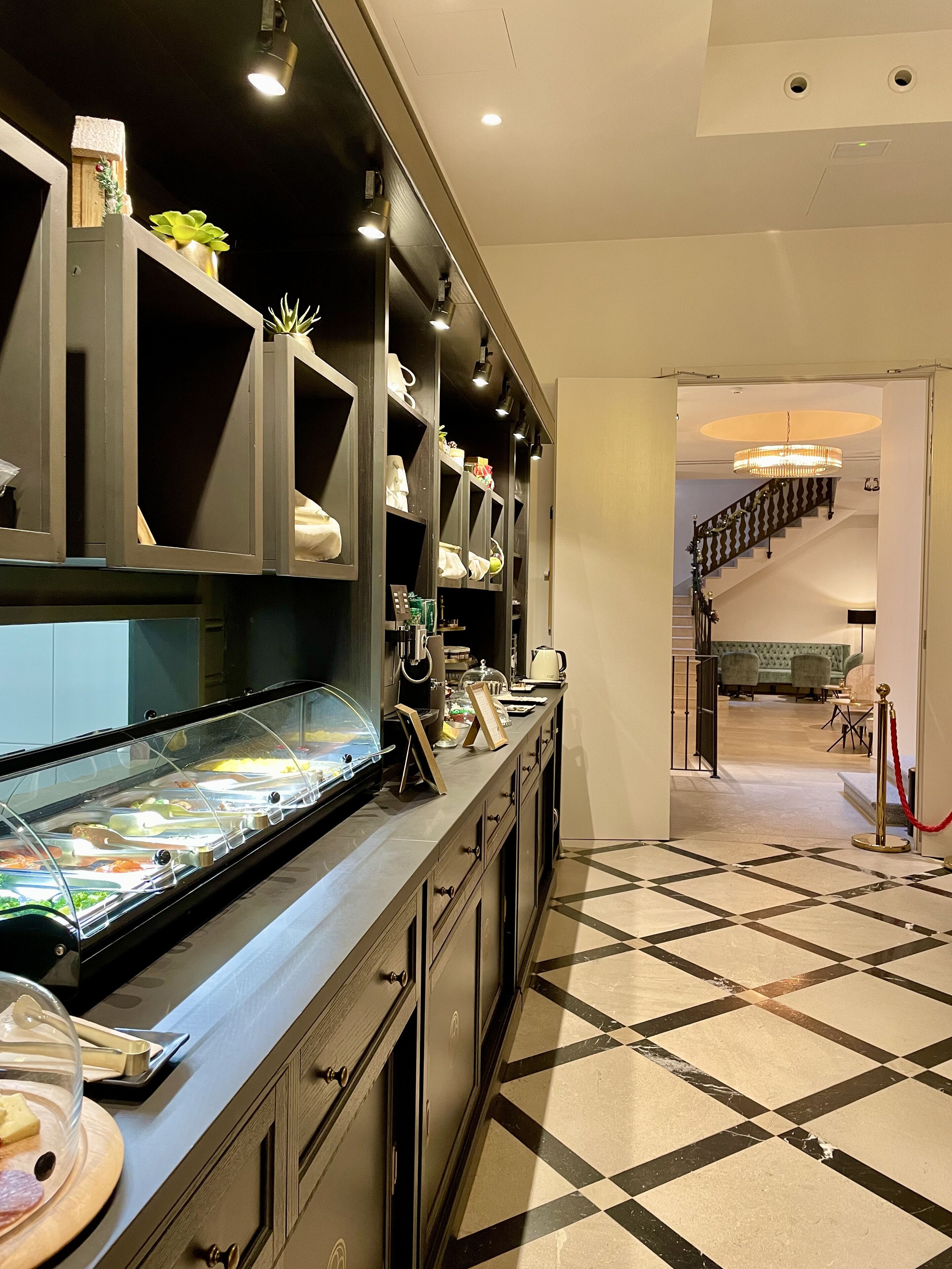 Een hotellobby met een receptiebalie, een buffetgedeelte en een trap naar de bovenverdiepingen.