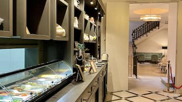 Een hotellobby met een receptiebalie, een buffetgedeelte en een trap naar de bovenverdiepingen.