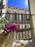 Un balcón con vistas a un edificio histórico de ventanas arqueadas y tejado de tejas.