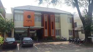 A multi-story building with a prominent orange sign reading "TIRTA mansion". - Tirta Mansion Premier (Curug)