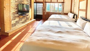 Una habitación con dos camas, un televisor montado en una pared de piedra y una ventana con cortinas.