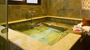 Un baño moderno con una bañera independiente, paredes de mármol y un panel decorativo de madera.