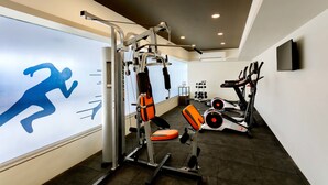 A gym with exercise equipment, a treadmill, and a wall with a running figure. - Ginger Aurangabad (Chhatrapati Sambhajinagar)