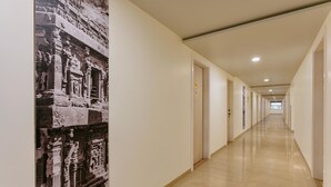 A long, narrow hallway with a polished floor, white walls, and a door at the end. - Ginger Aurangabad (Chhatrapati Sambhajinagar)