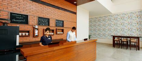 A reception area with a brick wall, wooden reception desk, and a tiled wall with a floral pattern.