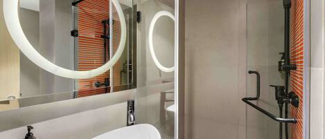 A modern bathroom with a large oval sink, a handheld showerhead, and a mirror with circular lights.