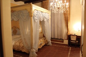 Ein Bett mit Baldachin, einer Kristallleuchtre und einem Schreibtisch mit Stuhl in einem Raum mit Fliesenboden.