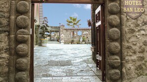 Entrada al Hotel San Leo con un arco de piedra y una señal encima.