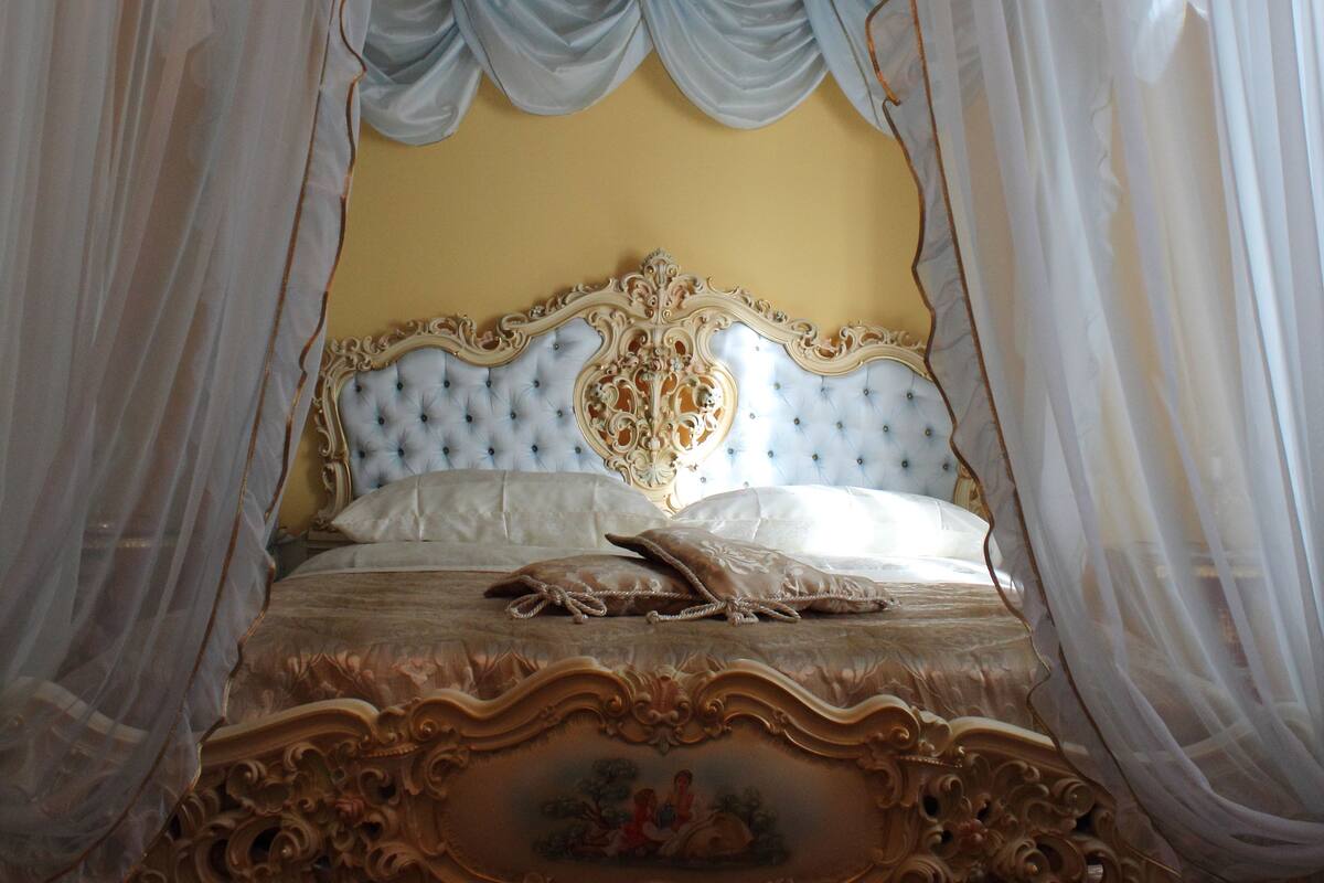 Una cama con dosel adornada con tallas ornamentales y cortinas drapeadas.