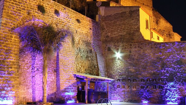 Una piscina con paredes de piedra y un edificio de arquitectura abovedada al fondo.
