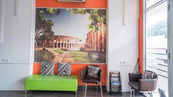 A lobby with a green sofa, two armchairs, and a large mural of an ancient structure.