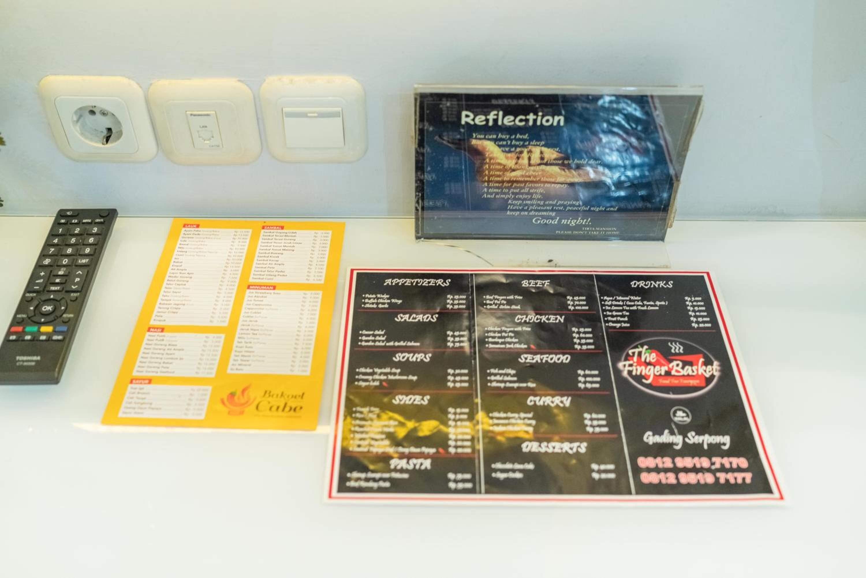Un panel de menú con diferentes categorías de comida y un CD titulado 'Reflection' sobre una mesa.