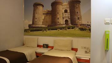 Een hotelkamer met twee bedden, een groot muurdecoratie van een kasteel en een groen nooduitgangsbord.