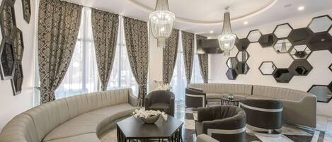 A modern living room with a curved sofa, a round coffee table, and a chandelier.