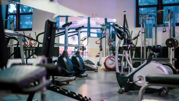A gym with various exercise equipment including treadmills, ellipticals, and weight machines.