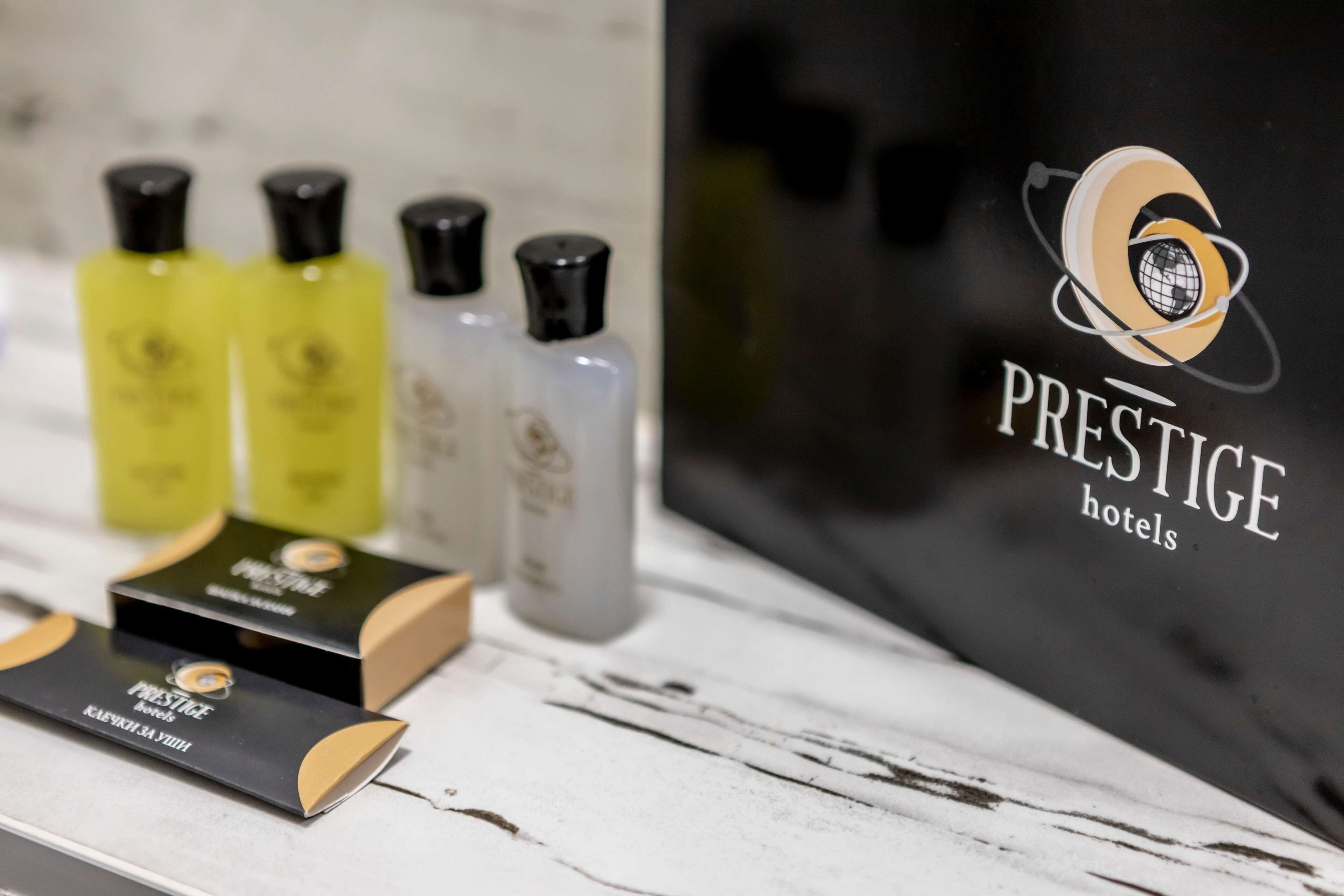 Presentación de productos de la marca Prestige Hotels, incluyendo botellas y cajas, sobre una superficie de mármol.