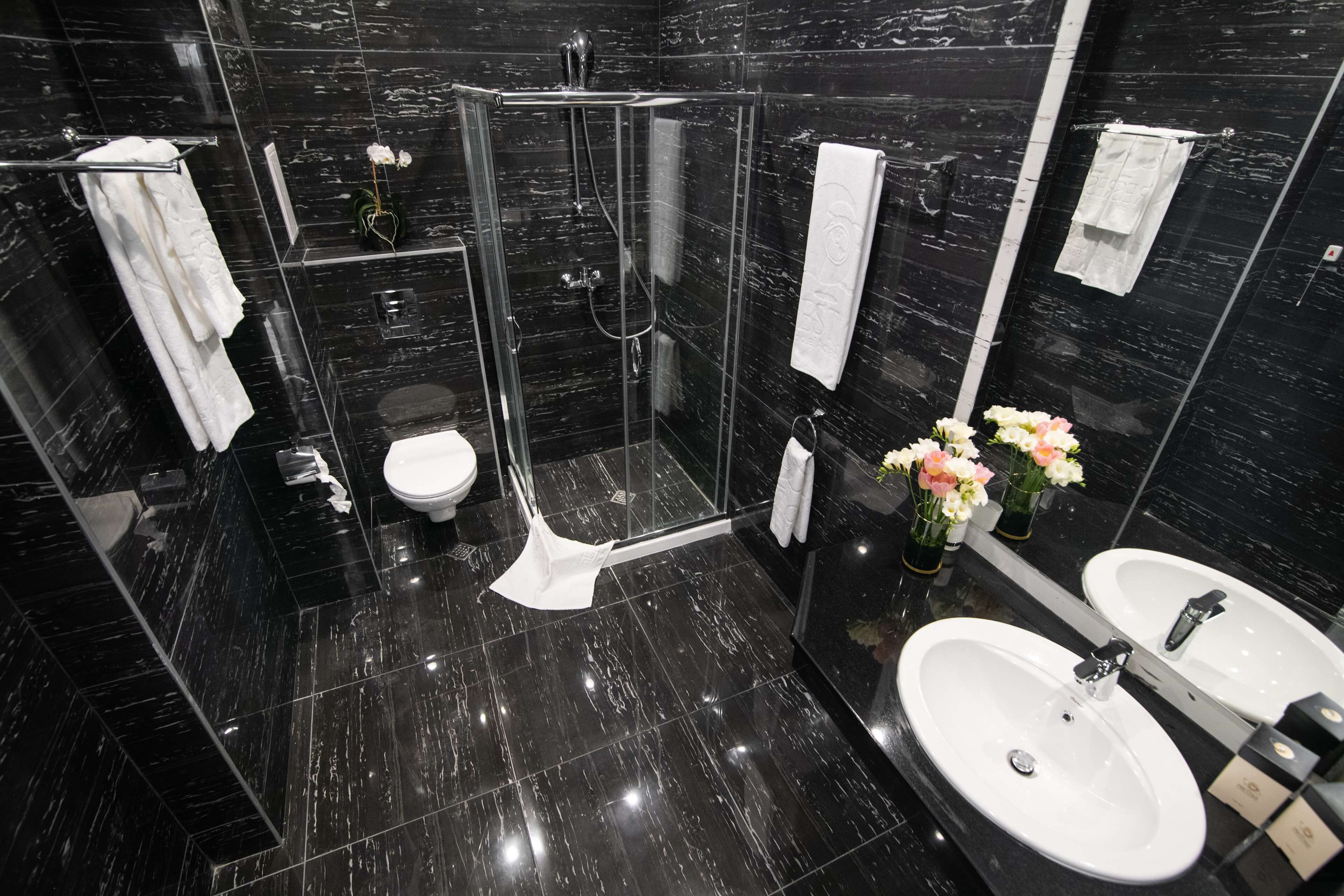 Un baño moderno con ducha de vidrio, inodoro y dos lavamanos.