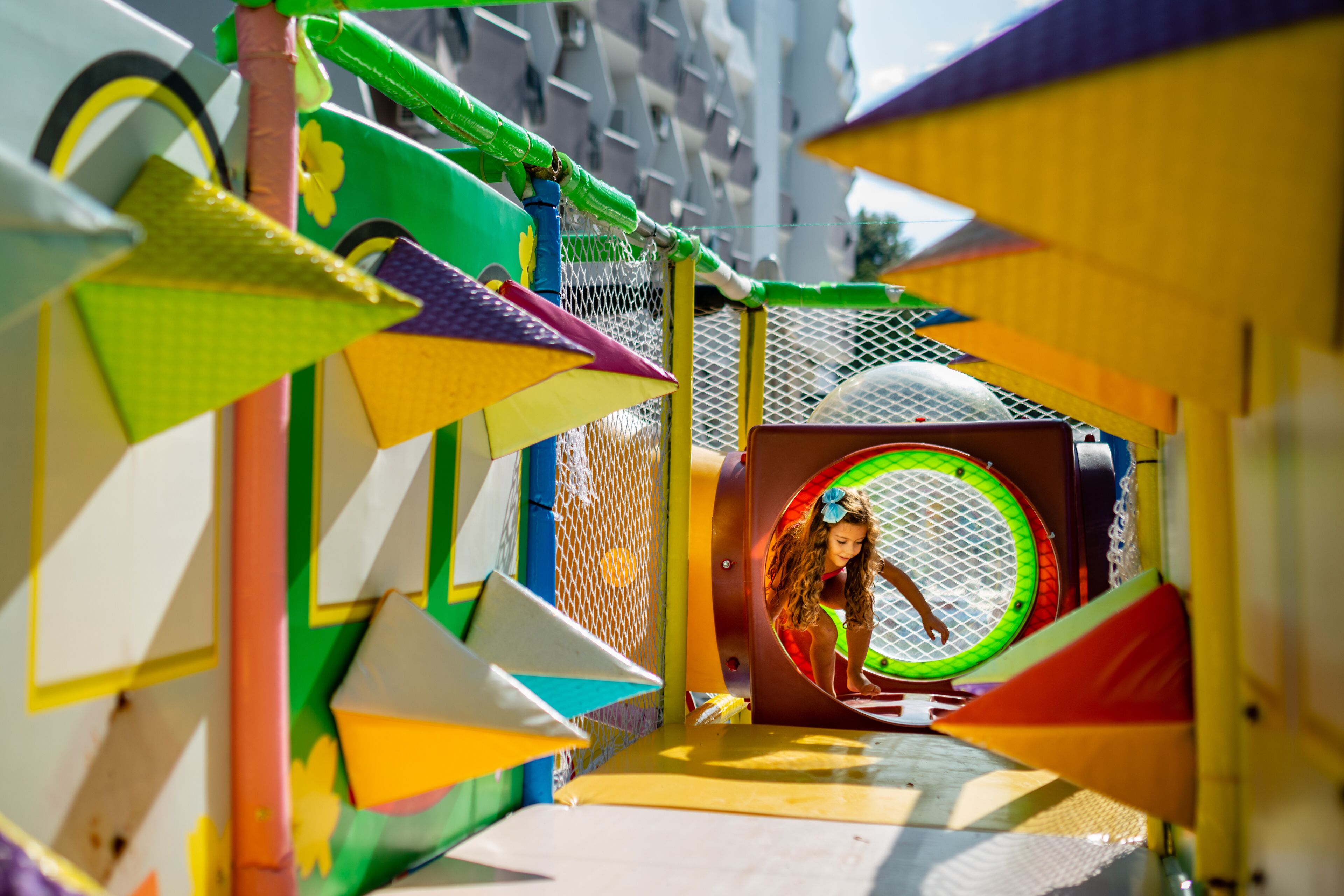 A colorful playground structure with a netted tunnel and slides.