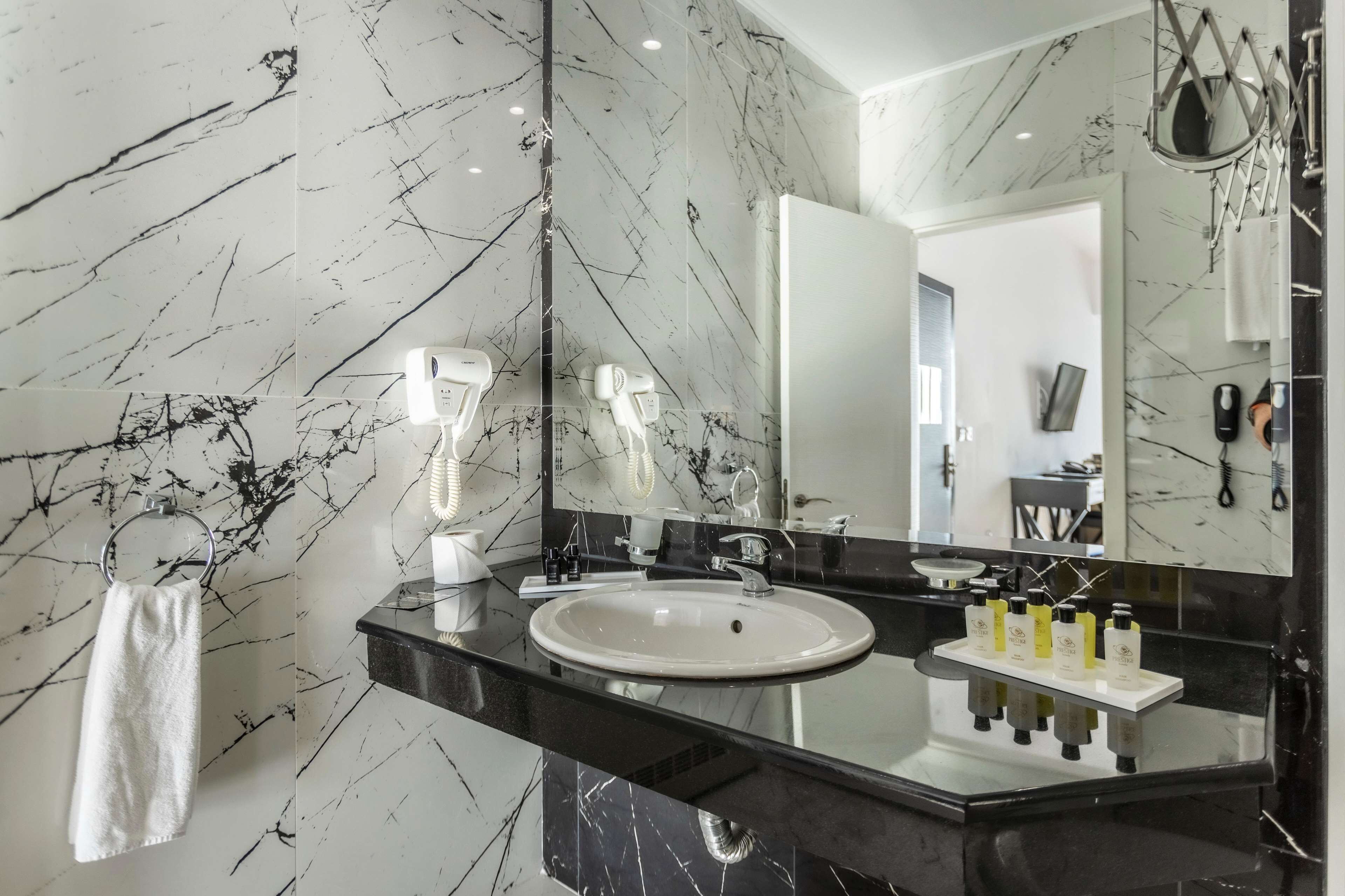 A modern bathroom with a marble backsplash, a round sink, and a large mirror.