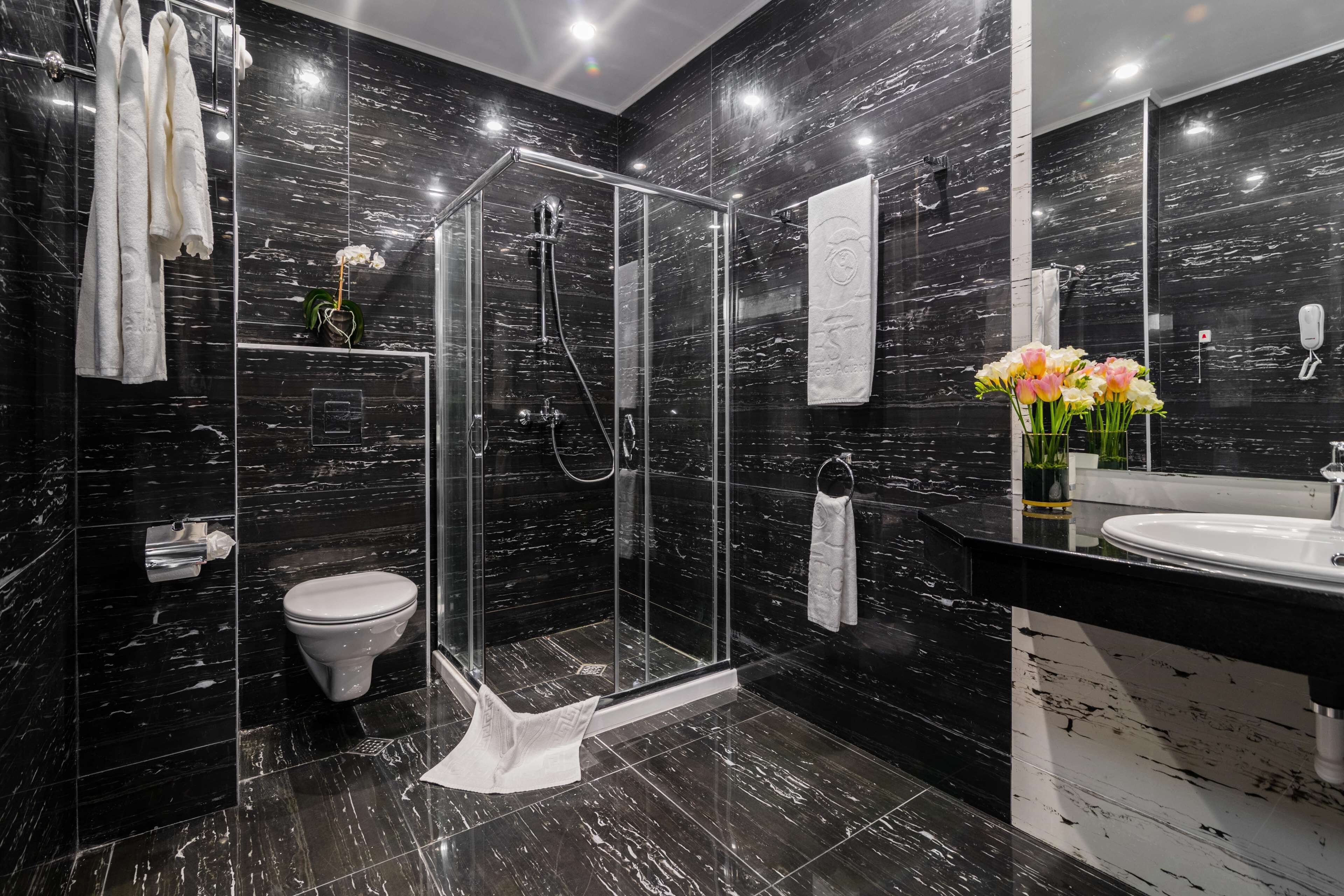 A modern bathroom with a glass-enclosed shower, a toilet, a sink, and a mirror.
