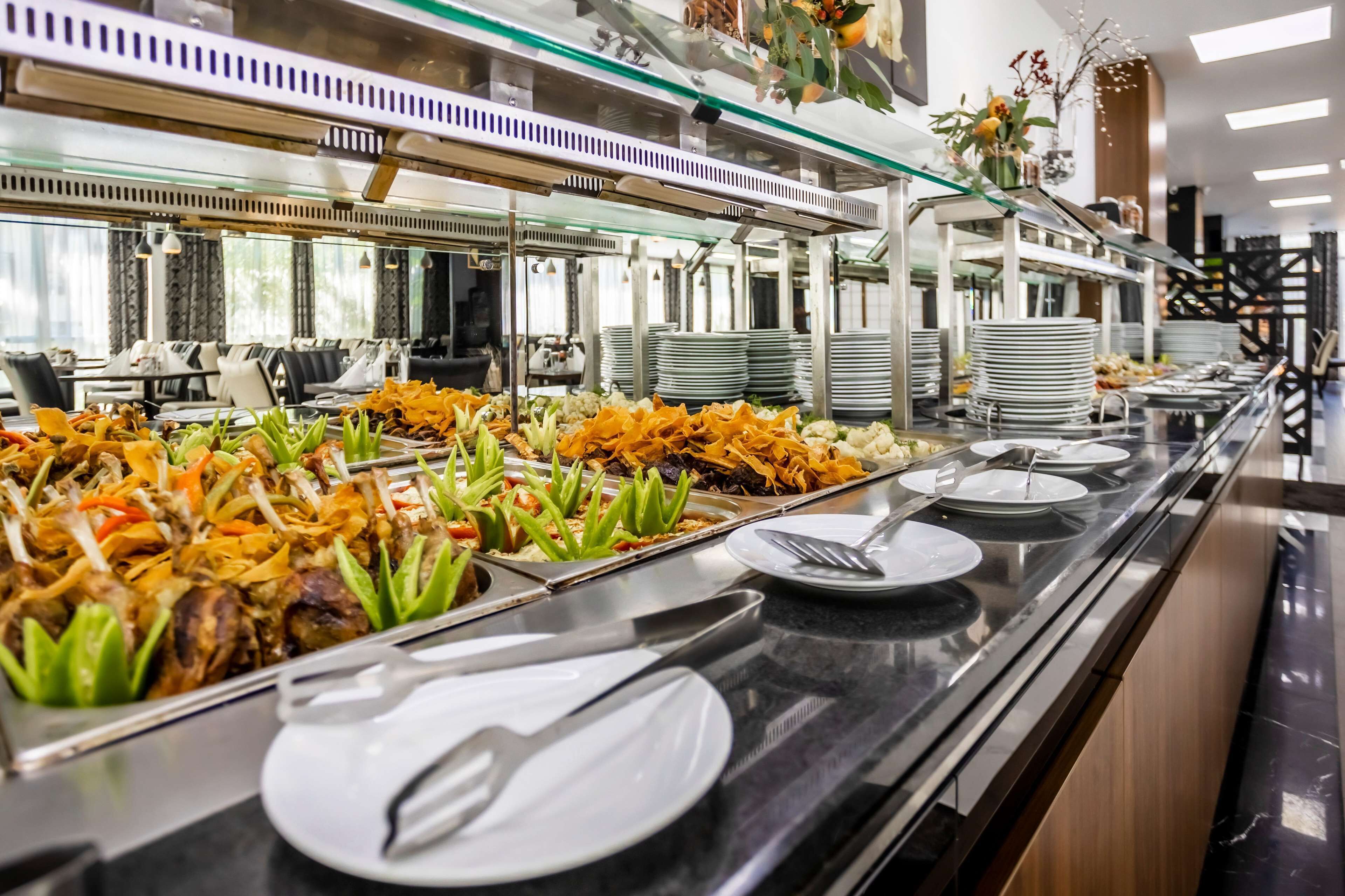 A buffet setup with various dishes, plates, and utensils.