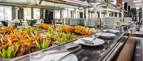 A buffet setup with various dishes, plates, and utensils.