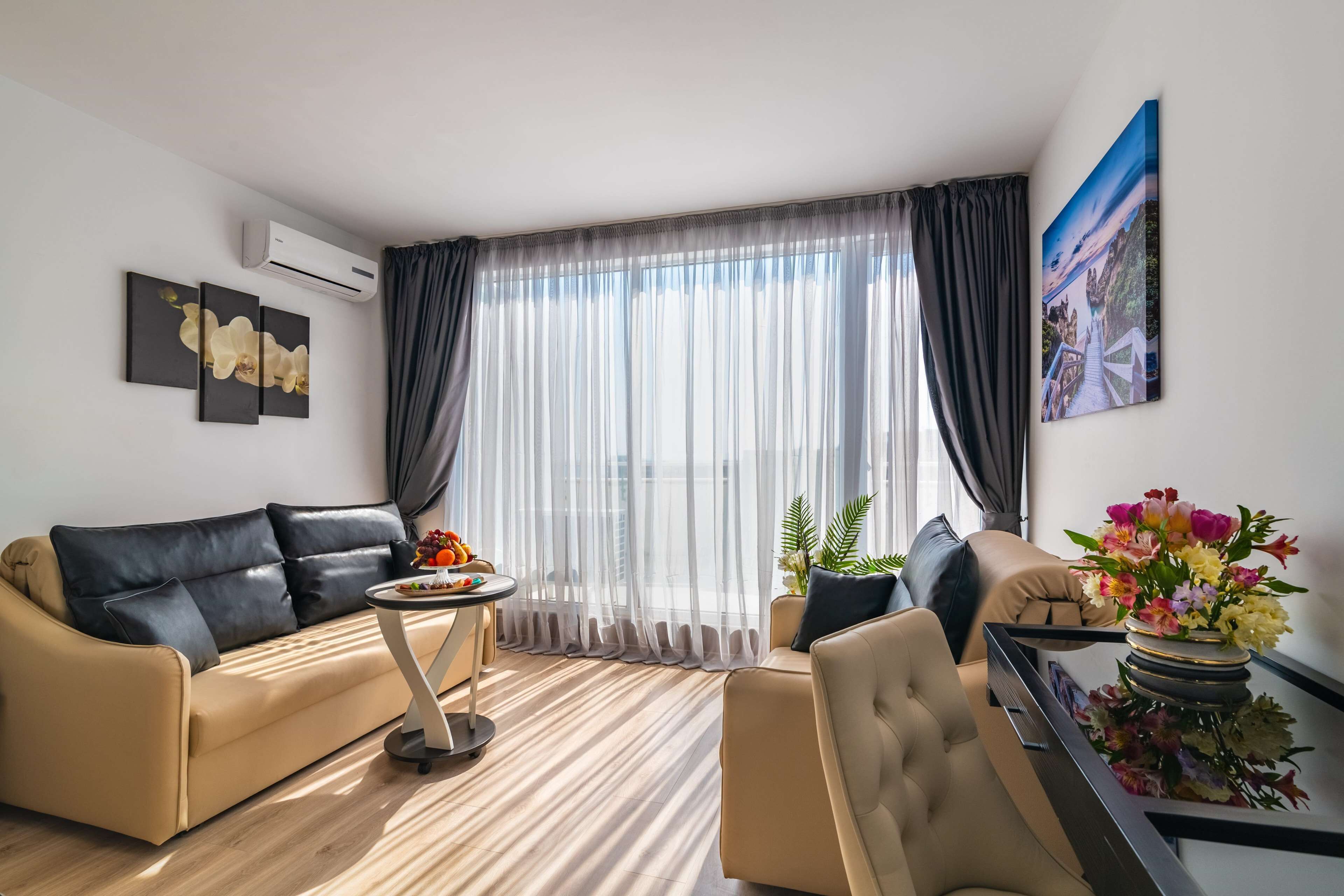 A modern living room with a sofa, armchair, and a small table with a vase of flowers.