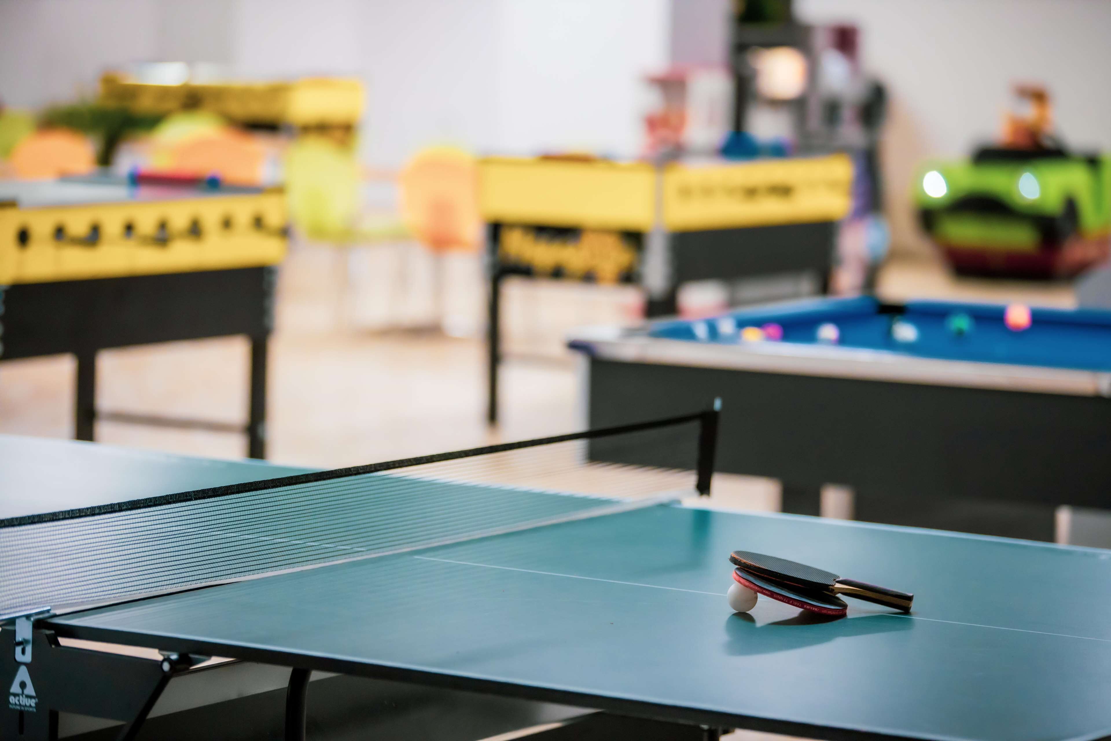 A ping pong table with a table tennis paddle in the foreground.
