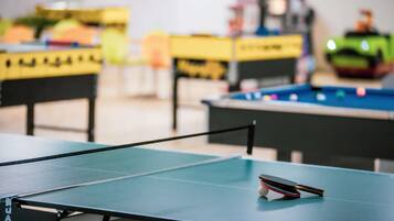 A ping pong table with a table tennis paddle in the foreground.