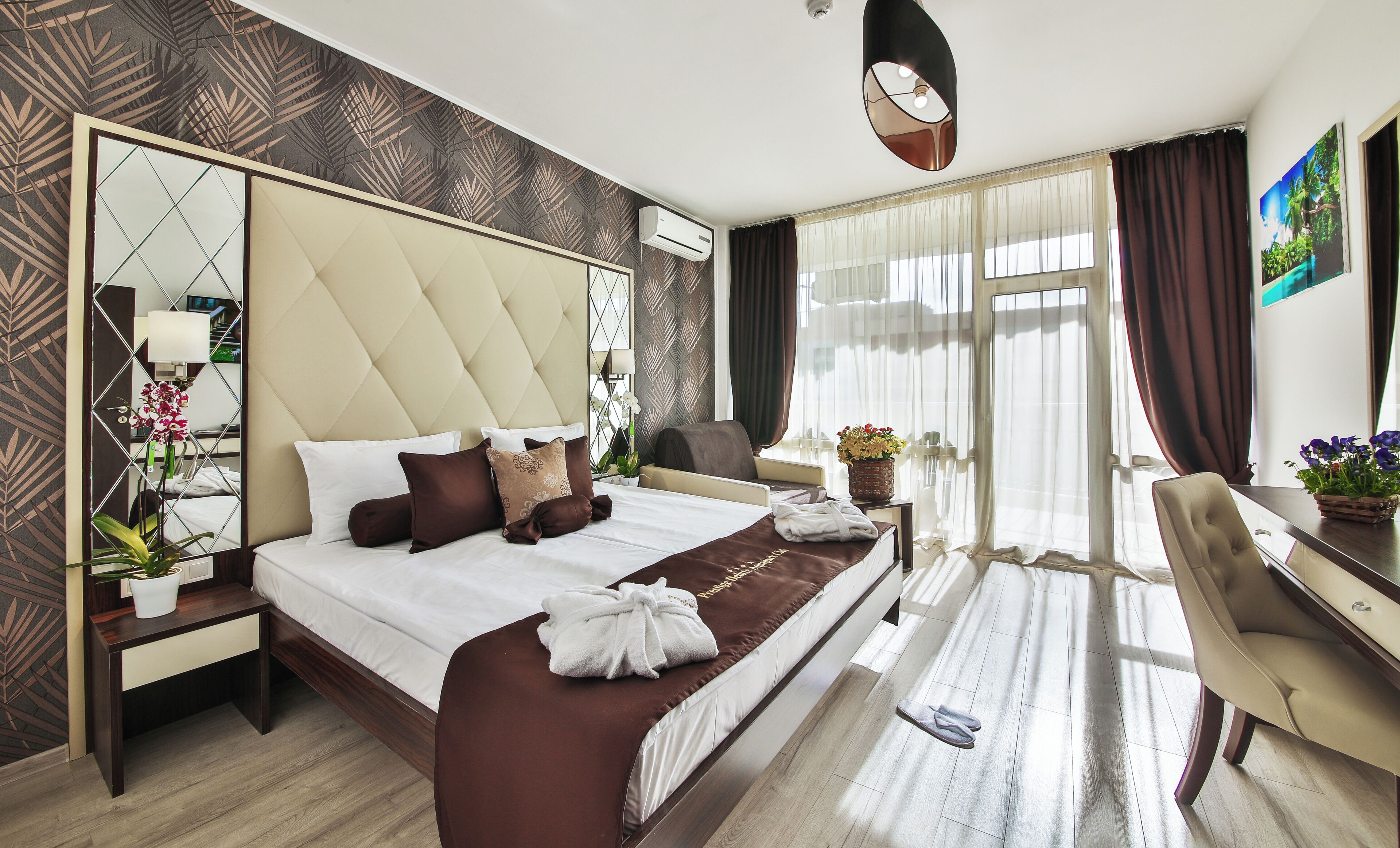 A hotel room with a large bed, a desk, a chair, a mirror, and a window with curtains.