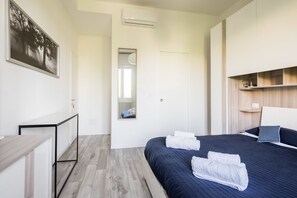 A modern hotel room with a bed, a desk, and a mirror. - Bologna Accommodation - Fiera (Bologna)