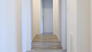 A hallway with wooden flooring, white walls, and a door at the end.