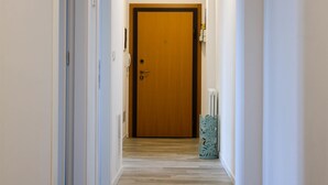 A hallway with a wooden door at the end, white walls, and a patterned floor.