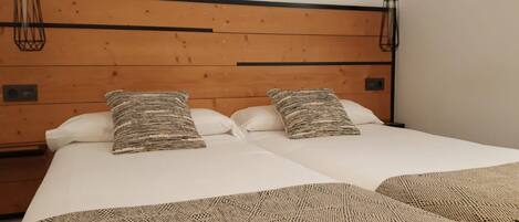 A double bed with two pillows, a wooden headboard, and a woven throw blanket.