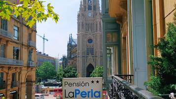 Straßenansicht mit einem großen Schild von Pension LaPerla, historischen Gebäuden und einem Dom im Hintergrund.