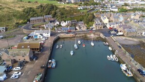 A coastal town with a marina, houses, and a hilly landscape in the background. - Gowan Bank (Montrose)