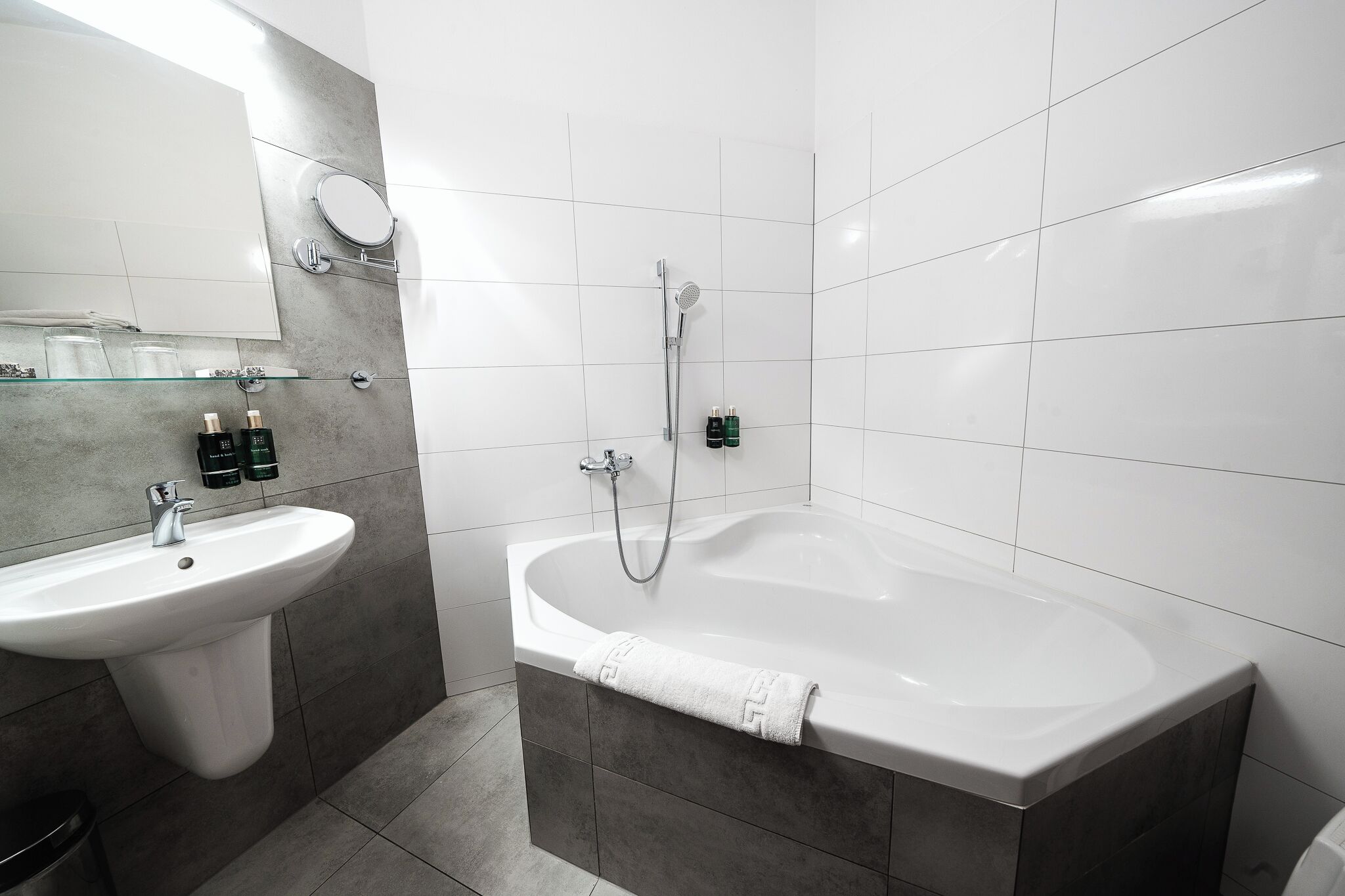 A modern bathroom with a sink, mirror, and bathtub.
