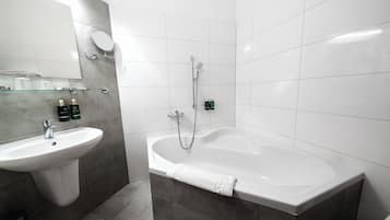 A modern bathroom with a sink, mirror, and bathtub.