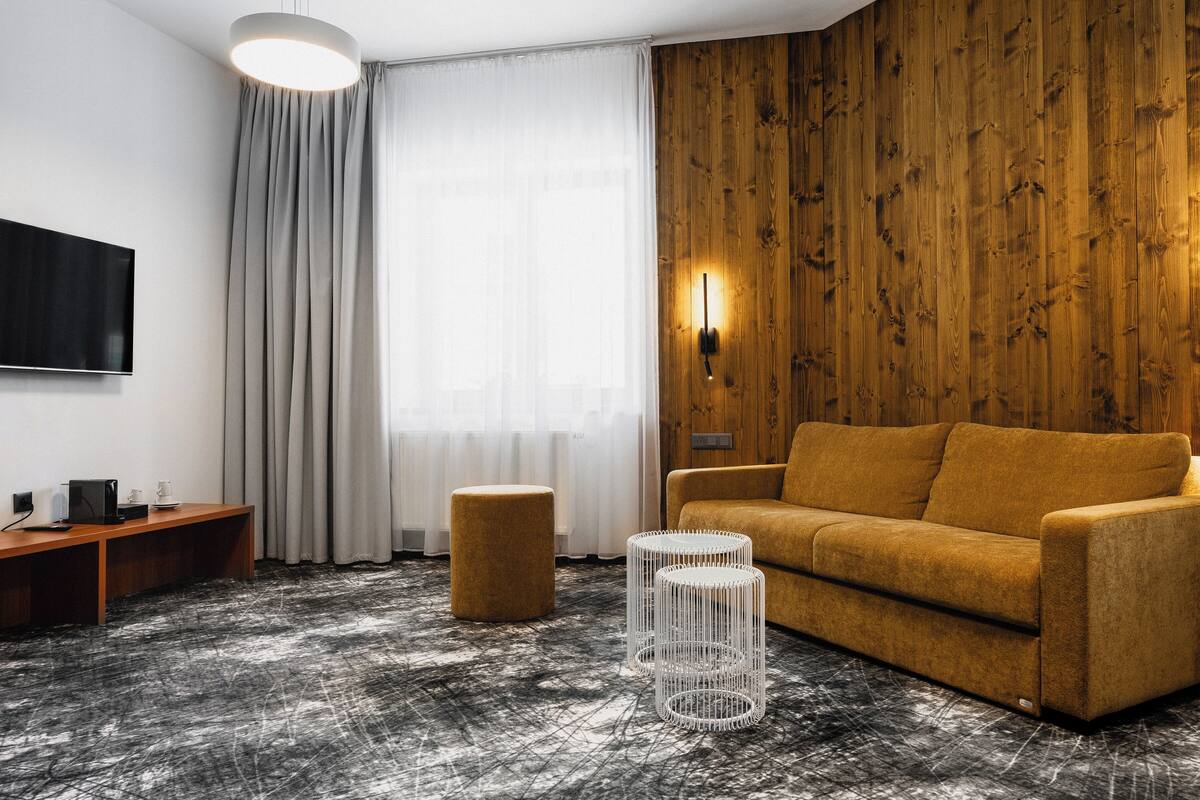 A modern living room with a wooden accent wall, a sofa, a coffee table, and a TV mounted on the wall.