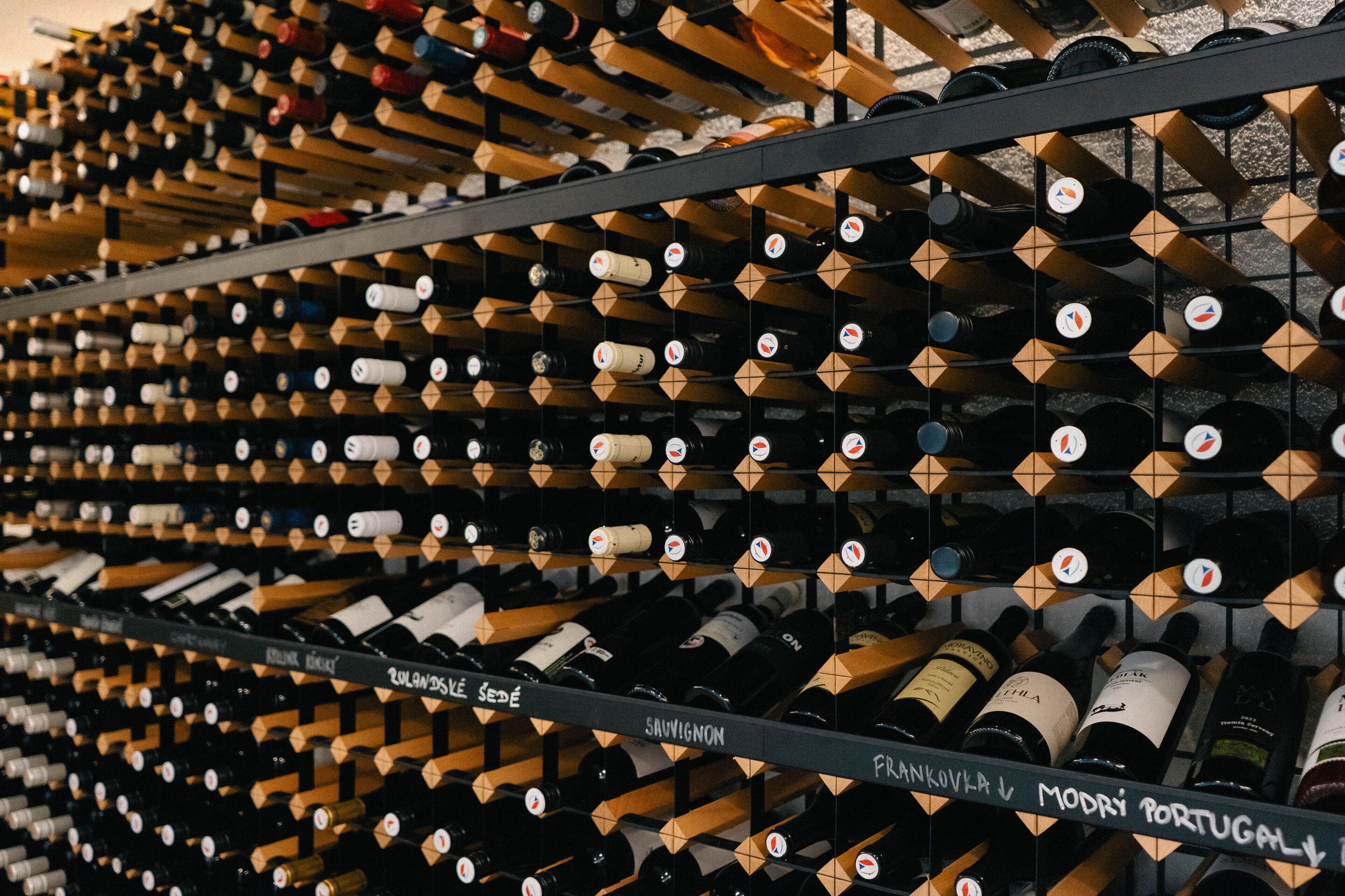 A wine cellar with rows of wine bottles on wooden shelves.