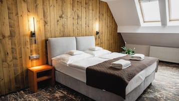 Un dormitorio con pared de madera, una cama con ropa blanca, una mesita de noche de madera y un radiador.