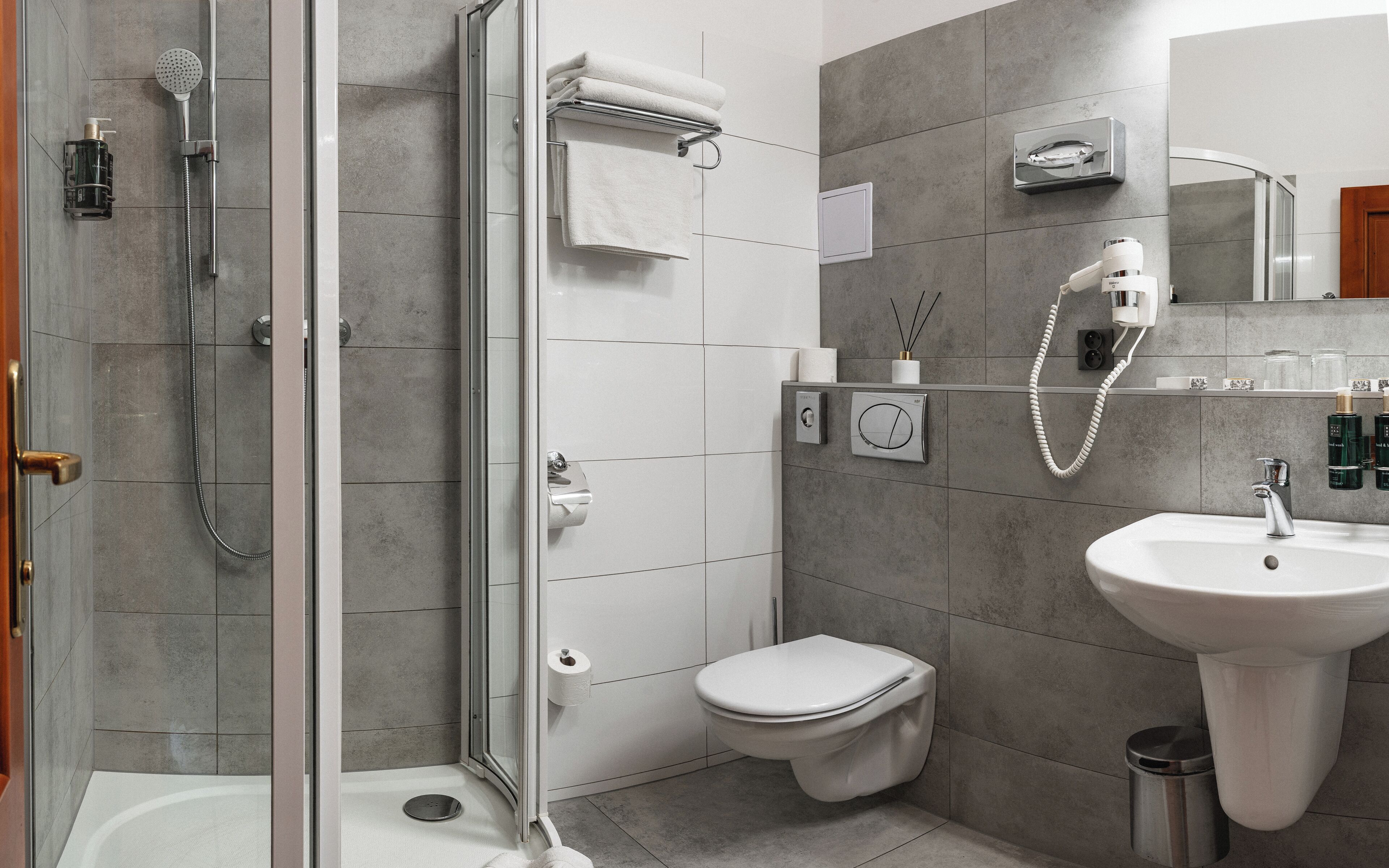 A modern bathroom with a glass-enclosed shower, a toilet, and a sink.