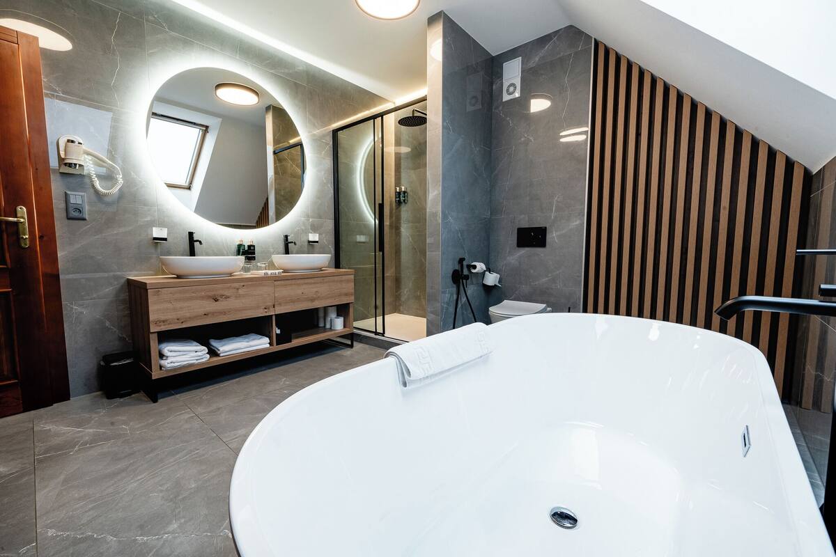 A modern bathroom with a freestanding bathtub, a vanity with a mirror, and a shower area.
