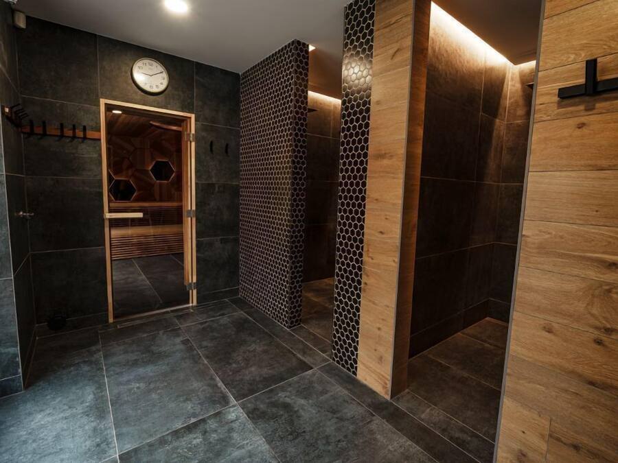 Een moderne badkamer met donkere tegels, een houten deur en een wand met een honingraatpatroon.